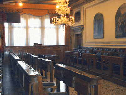 Sala del Consiglio - particolare banchi in legno, quadri alle pareti e lampadario di Murano