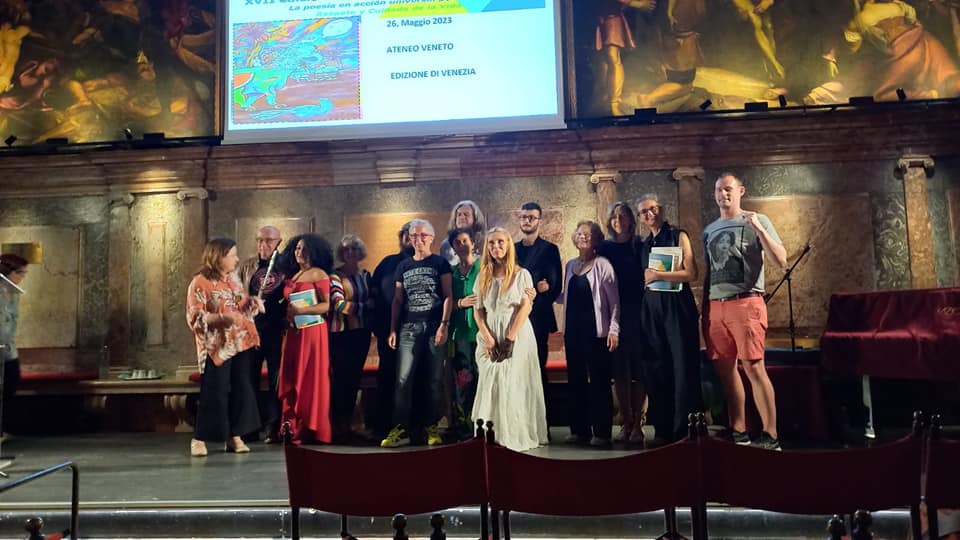 14 persone, tra uomini e donne, in posa su un palco