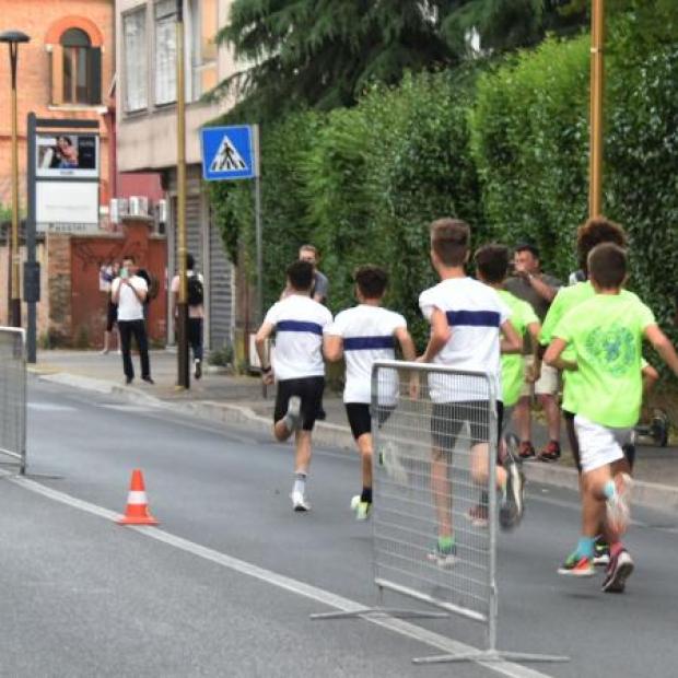 Dei giovani podisti visti di spalle corrono su una strada urbana