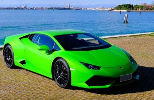 Una Lamborghini parcheggiata su una riva del Lido, sullo sfondo la laguna