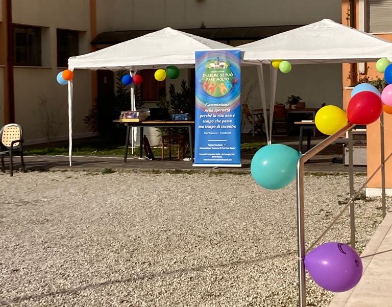 In primo piano, palloncini colorati appesi a un corrimano; sullo sfondo, due gazebo