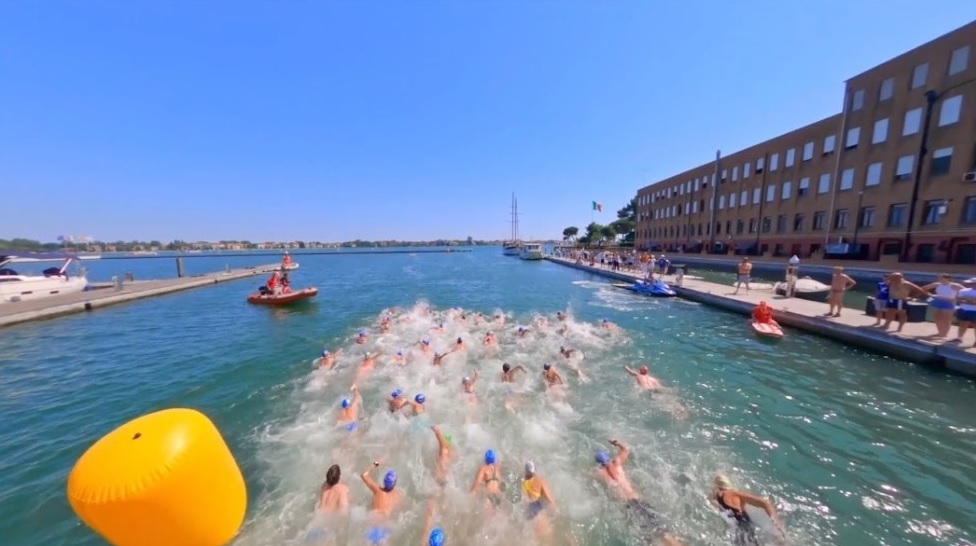 Folto gruppo di nuotatori gareggia in un tratto di laguna adiacente a Venezia