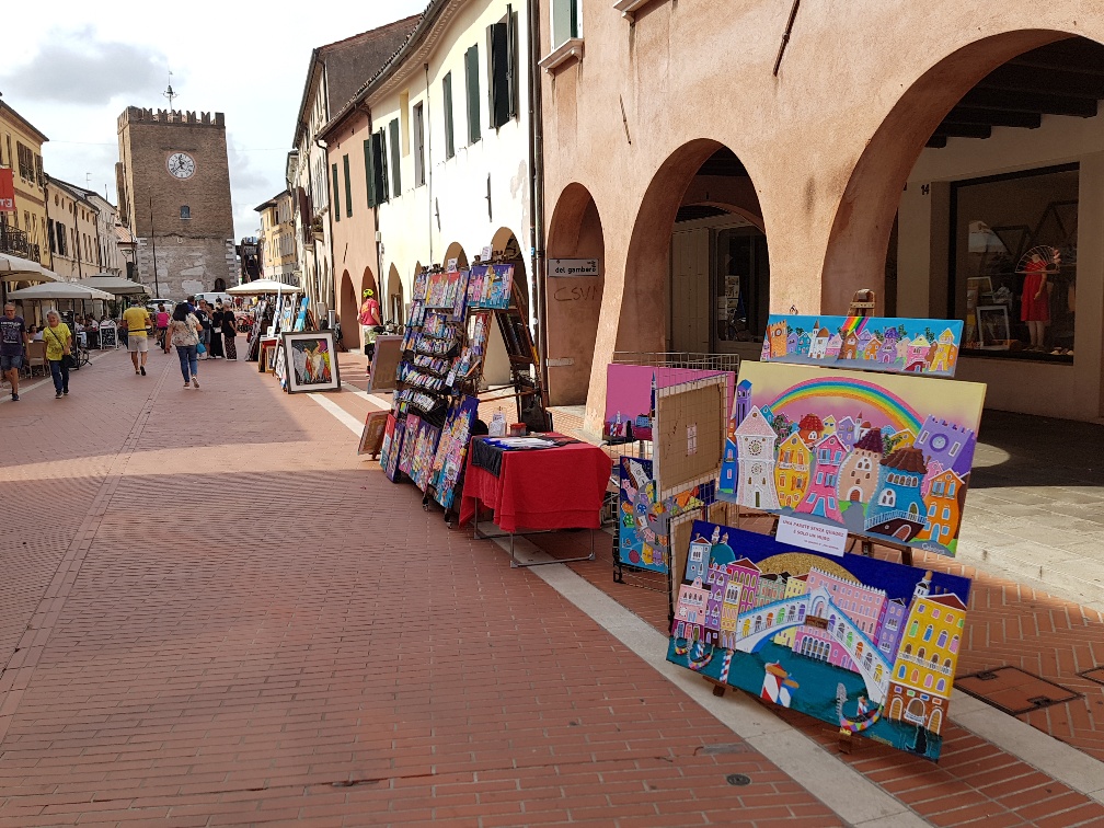 Quadri esposti all'aperto, su cavalletti, in una via cittadina