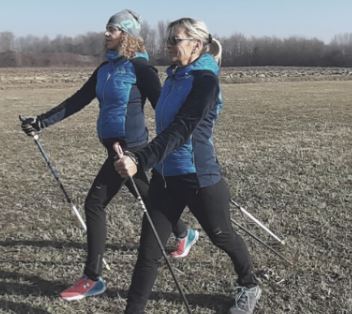 Due donne praticano nordic walking in un campo
