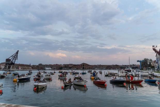 Piccole barche allineate in uno specchio d'acqua di fronte a una gru portuale